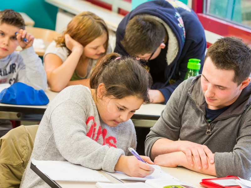 Eine Schülerin mit Kopftuch unterhält sich mit einem Schüler, der einen Hut trägt